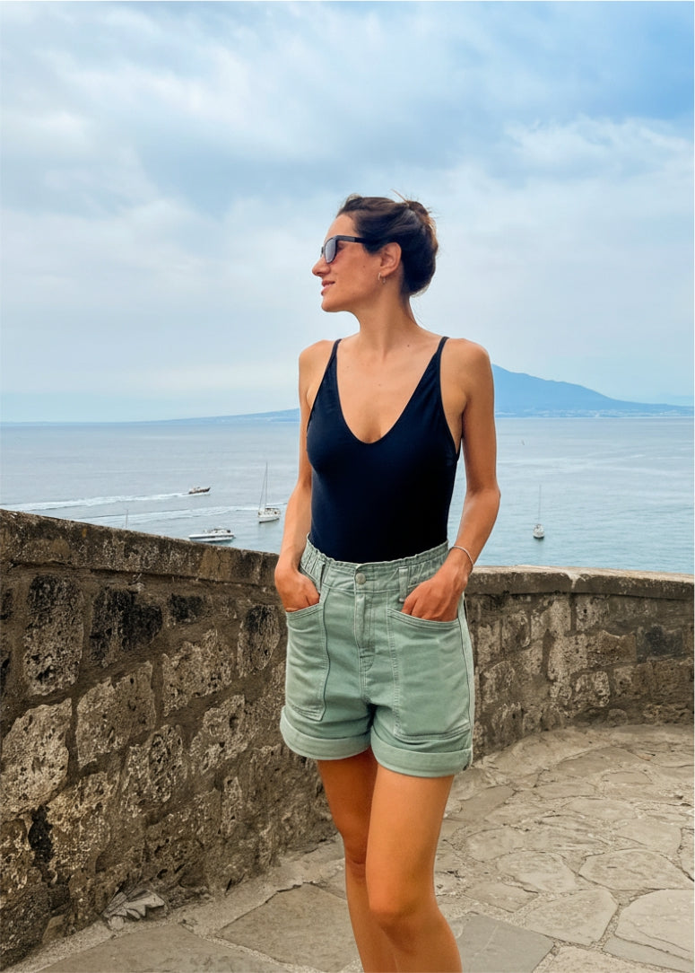 Bañador de mujer diseñado en tejido de licra satinado color negro - modelo caminando y luciendo el bañador