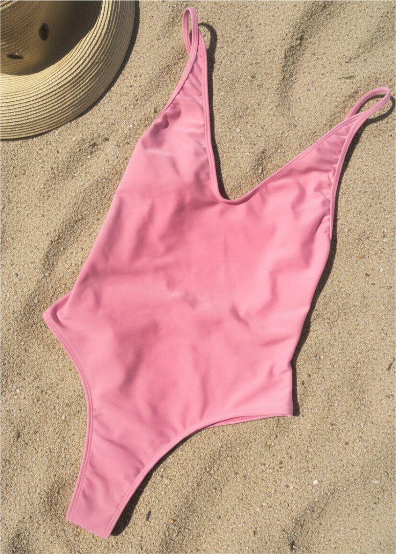 Bañador con tirantes regulables en color rosa - vista de frente sobre la arena
